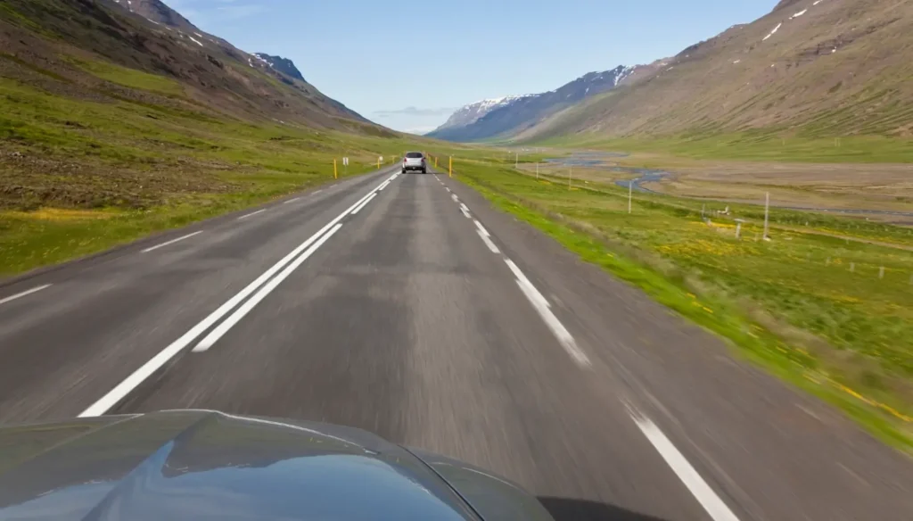 Vehicles driving on a paved road in Iceland on a sunny day