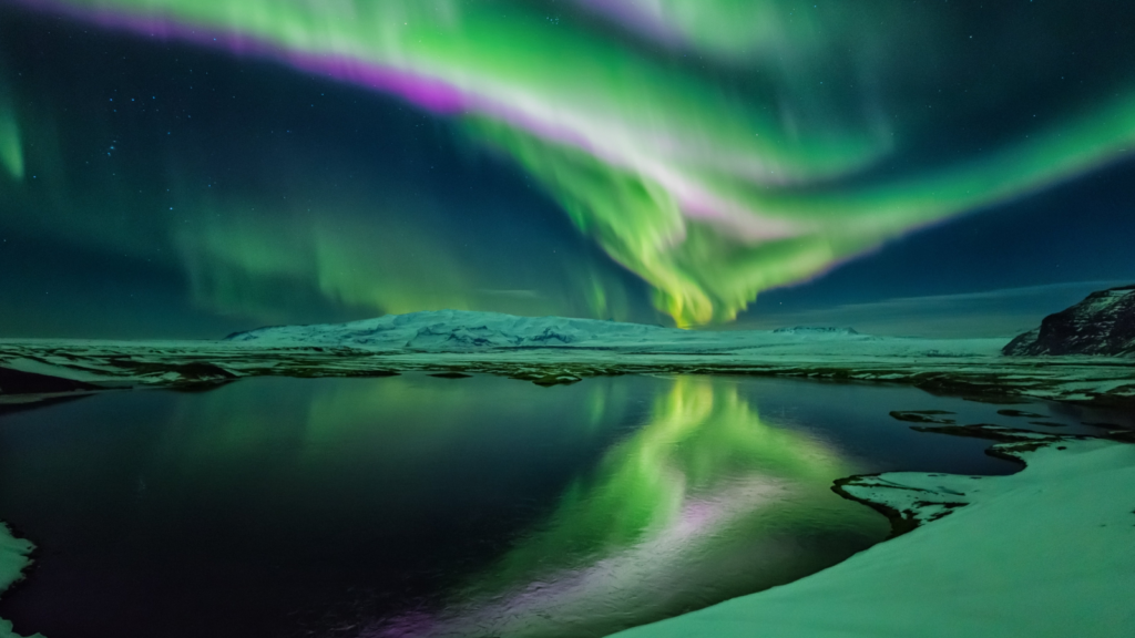 Green and purple Northern Lights over a lake in Iceland