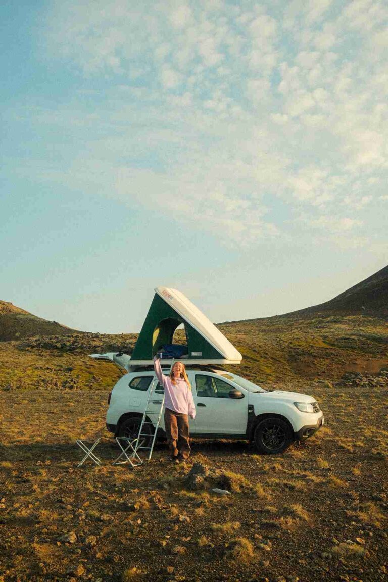 Dacia duster with open tent and a woman standing outise with camping chairs