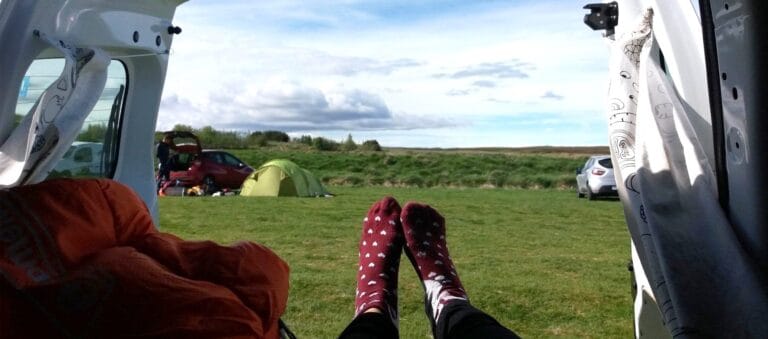person lying in an open camper van in a campsite