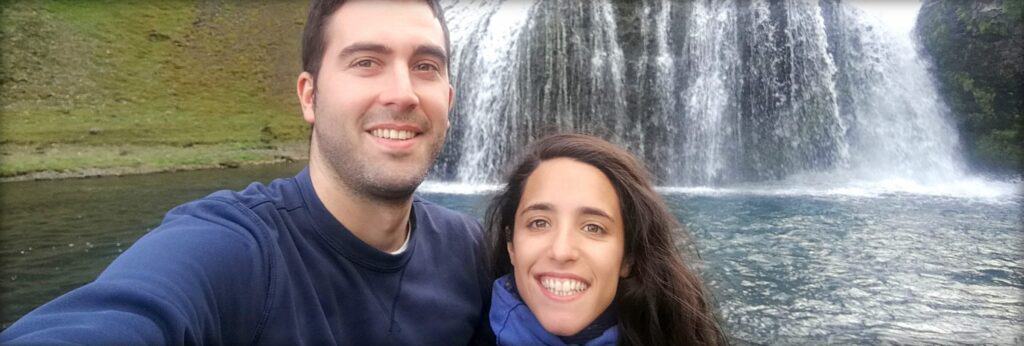 a couple in front of a lake and waterfall
