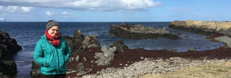 woman standing at a beach with the sea in the background