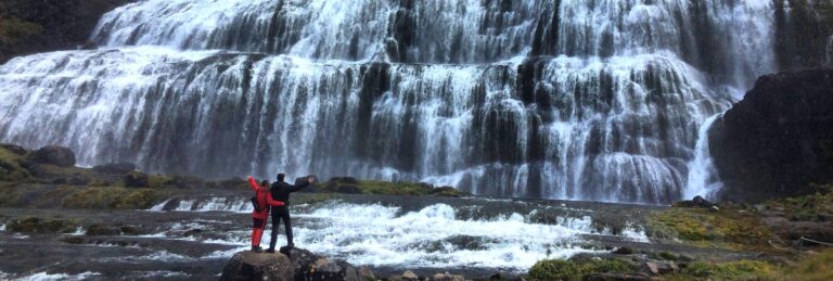 couple holding out hands in front of a waterfall