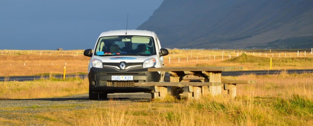 rent.is camper parked next to a bench in the sun