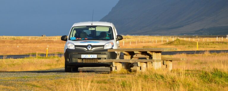 rent.is camper parked next to a bench in the sun