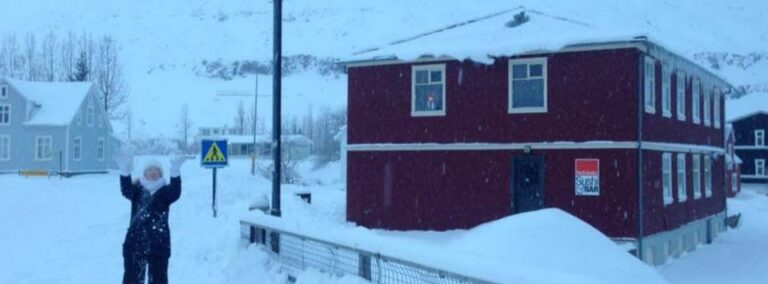 woman standing in snow next to a house in Iceland