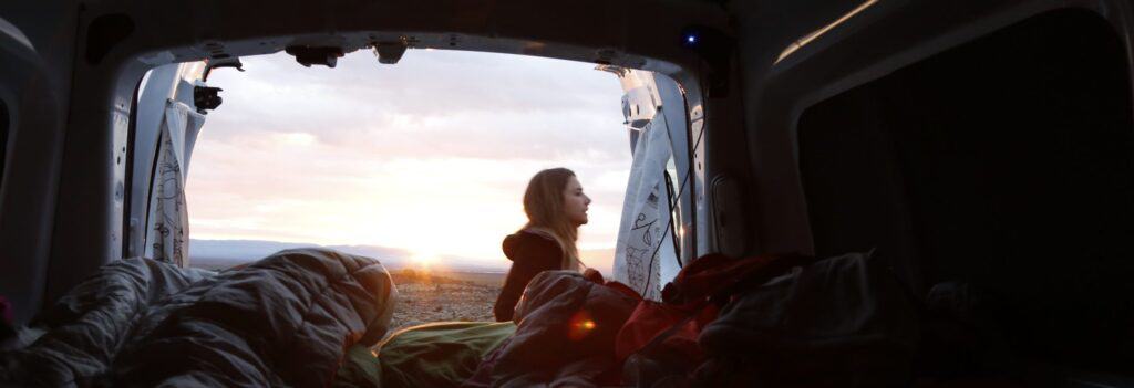 Sleepingbags inside camper woman standing outside