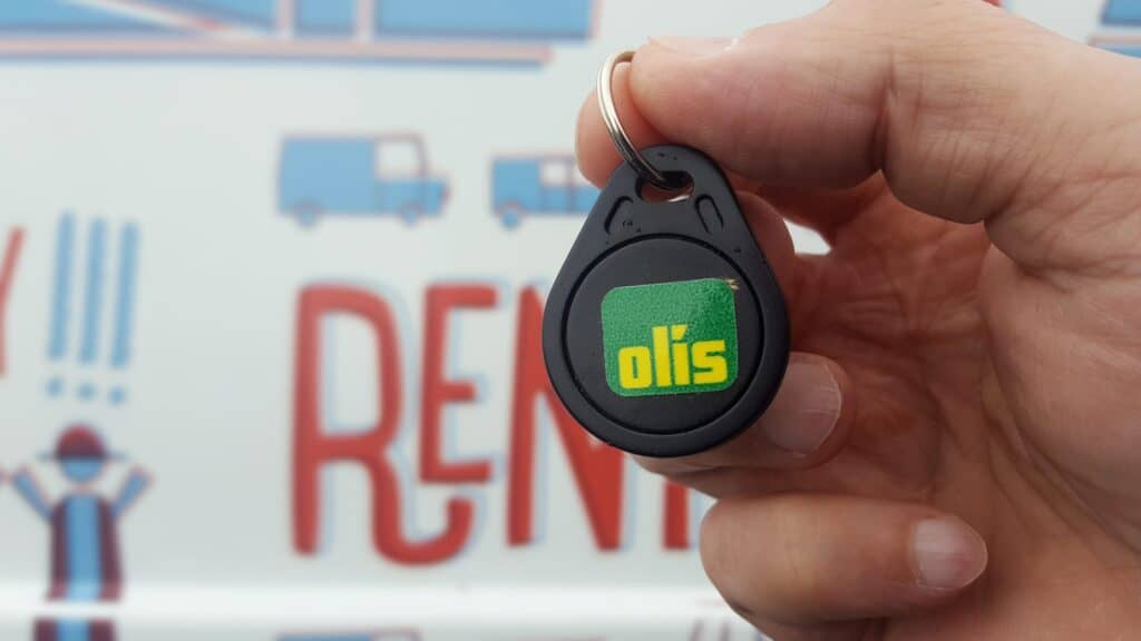 An Olís key tag held in front of a Rent.is camper
