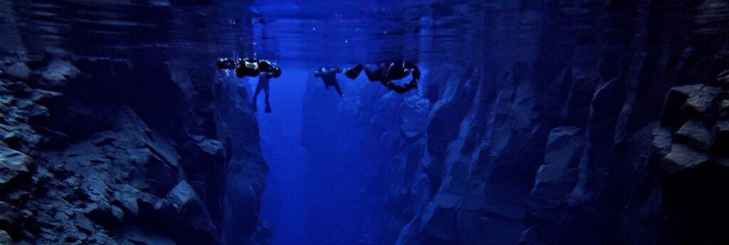 people snorkeling in silfra between cliffs