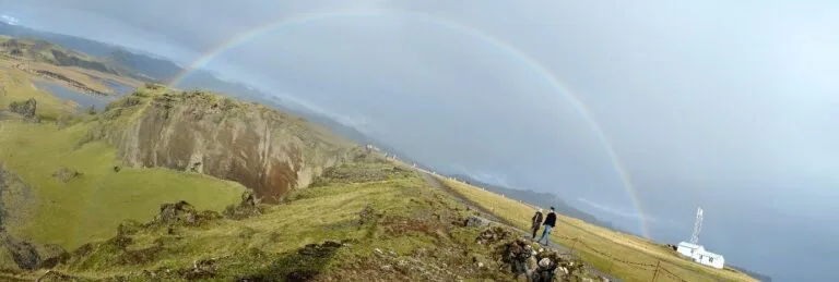 people undar a rainbow in the icelandic nature