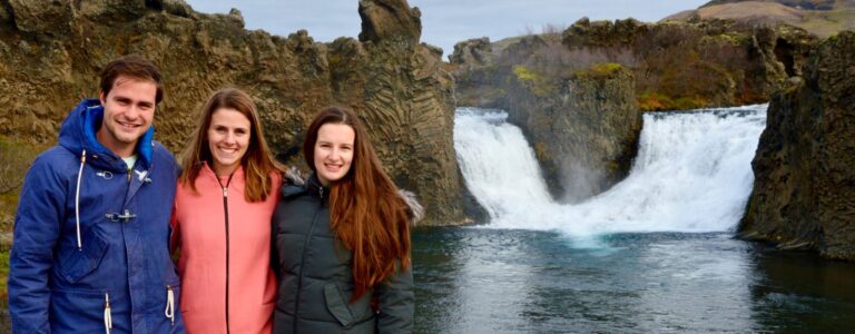 one man and two women in front of a waterfall in Iceland
