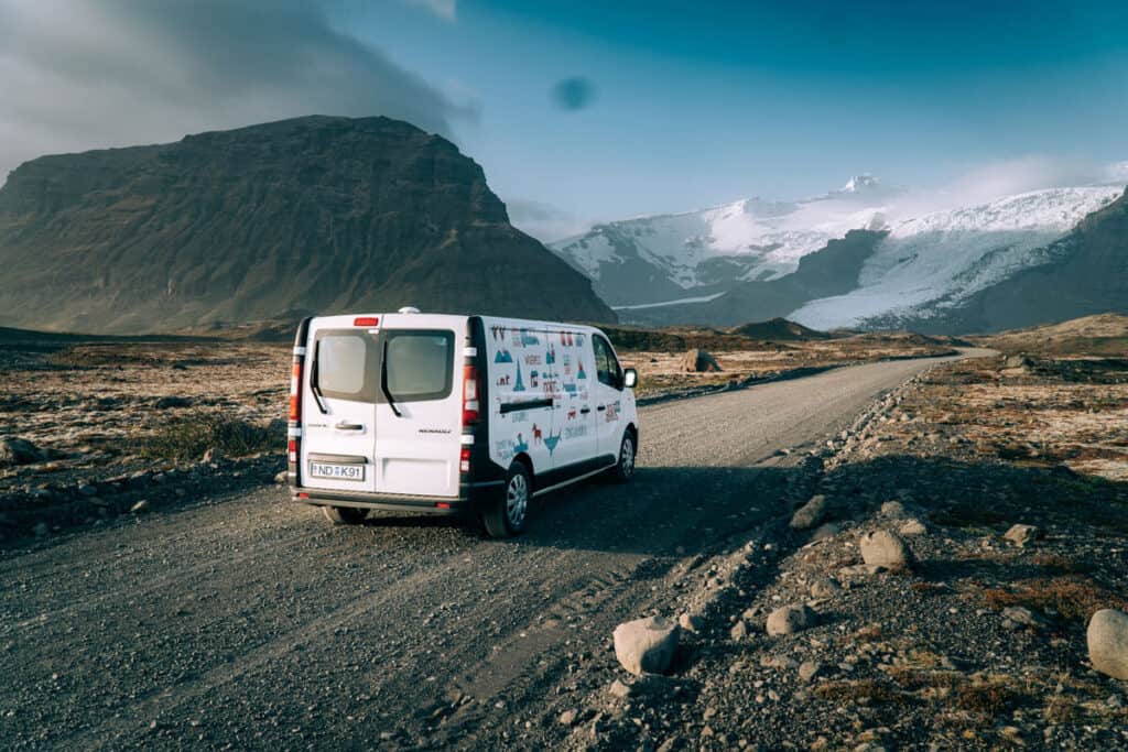 Rent.is camper traveling on a gravel road towards a glacier.