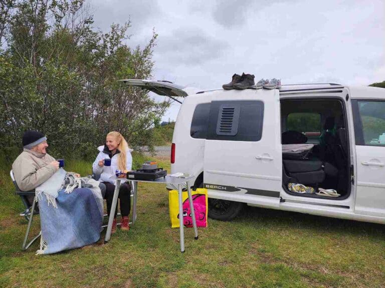 A couple sits and eats by the vw Caddy