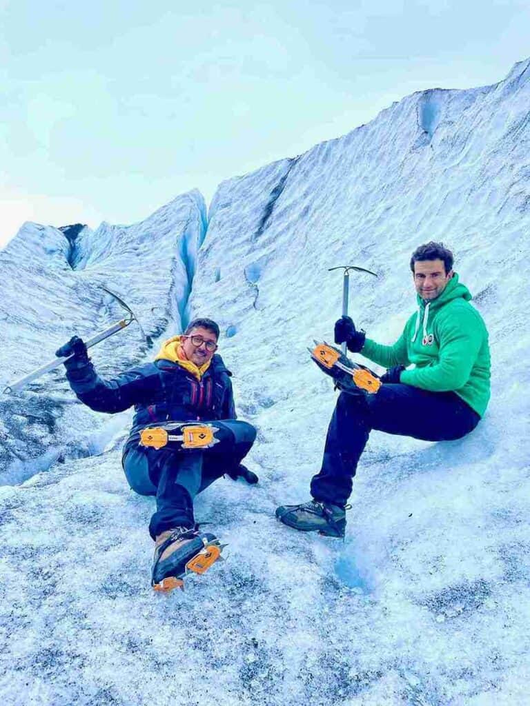 Two men sitting on a glacier and climbing