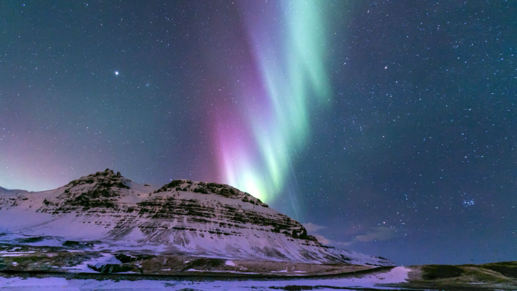 Northern Lights over snowy mountains in Iceland.