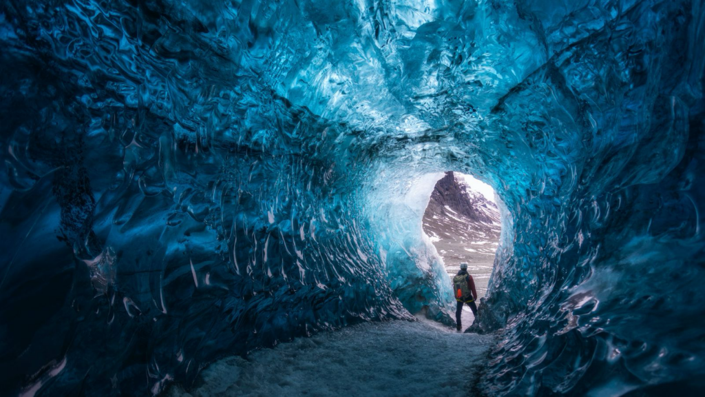 Man standing in a blue ice cave in Iceland.