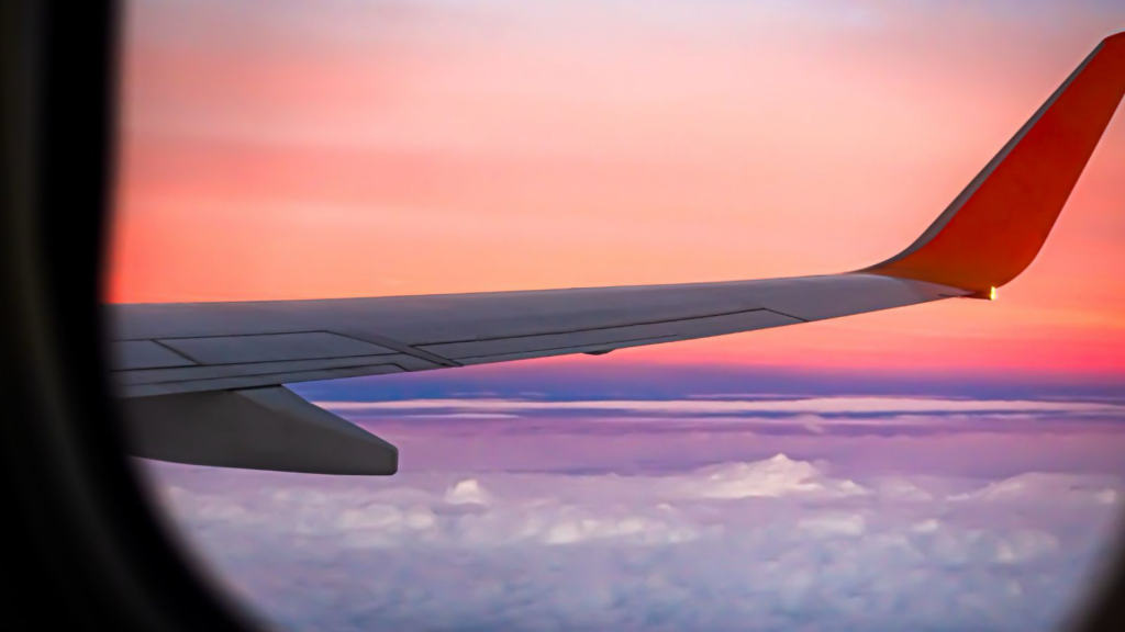 View of an aircraft wing out a plane window at sunset.