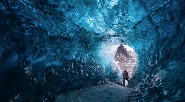 Person exploring a blue ice cave in Iceland.