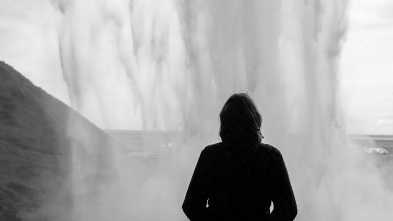 Solo traveler standing behind Seljalandsfoss waterfall in Iceland