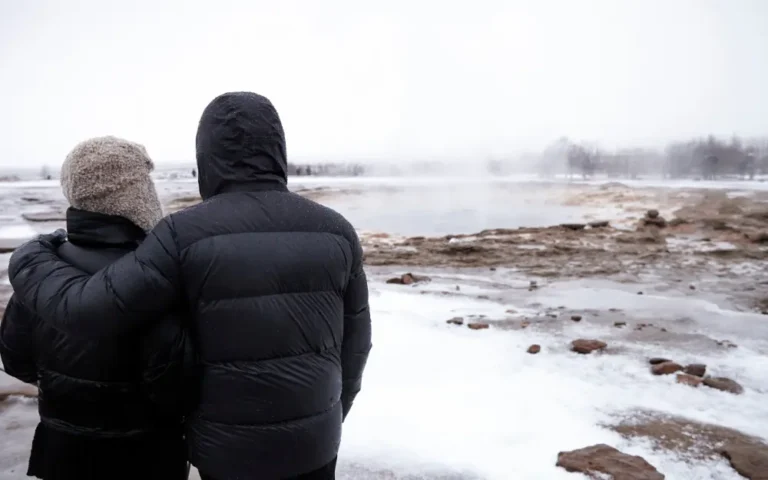 Couple standing in front of a geothermal pool in Iceland