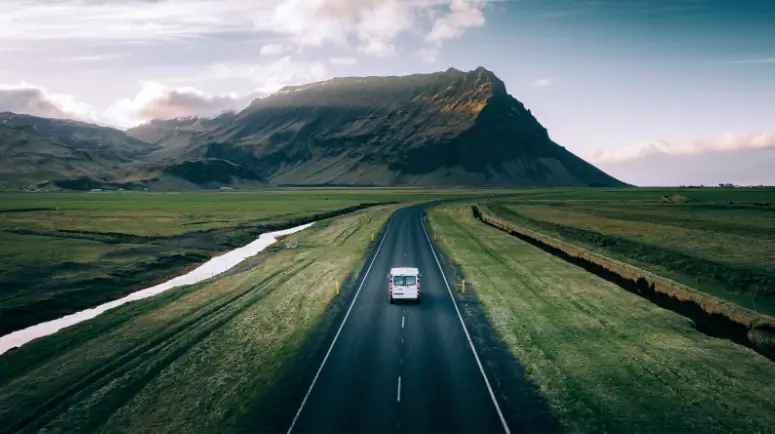 Camper van driving along an open Icelandic road.