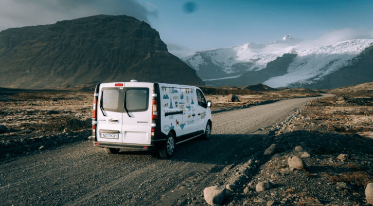Camper van on a rural road in Iceland with a glacier in the distance.