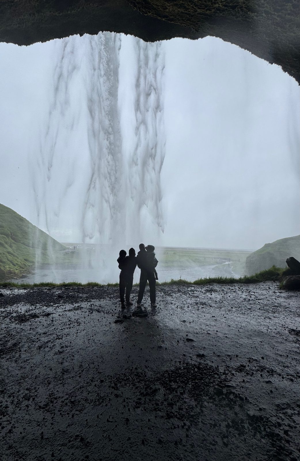 Family silhouetted on the path behind Seljalandsfoss waterfall