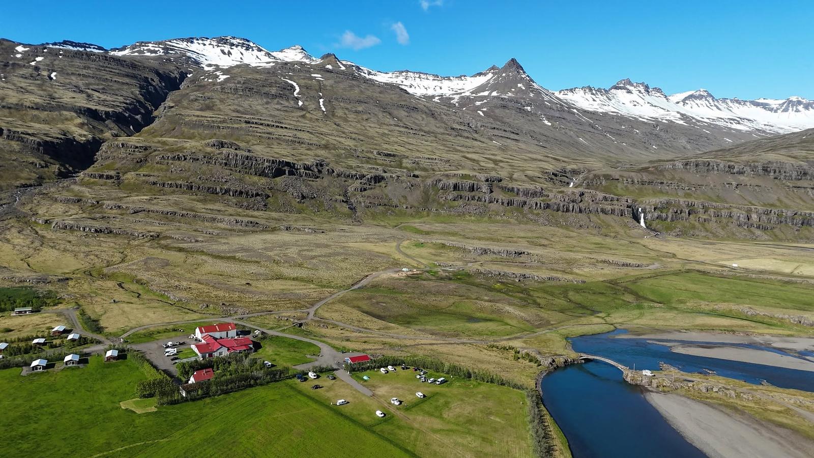 Aerial view of Bragðavellir campground beneath snow-capped mountains in the East Fjords