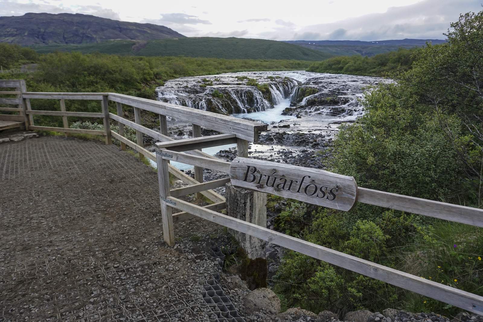 Wooden Brúarfoss sign at the viewing platform above the blue waterfall