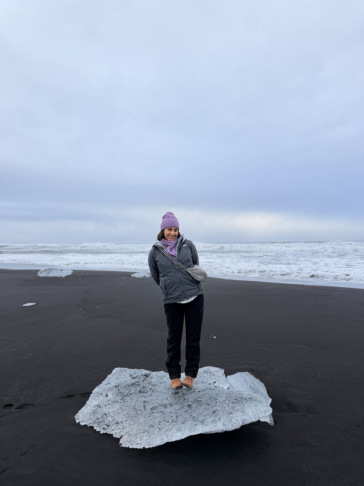 Standing on a block of glacier ice on the black sand of Diamond Beach