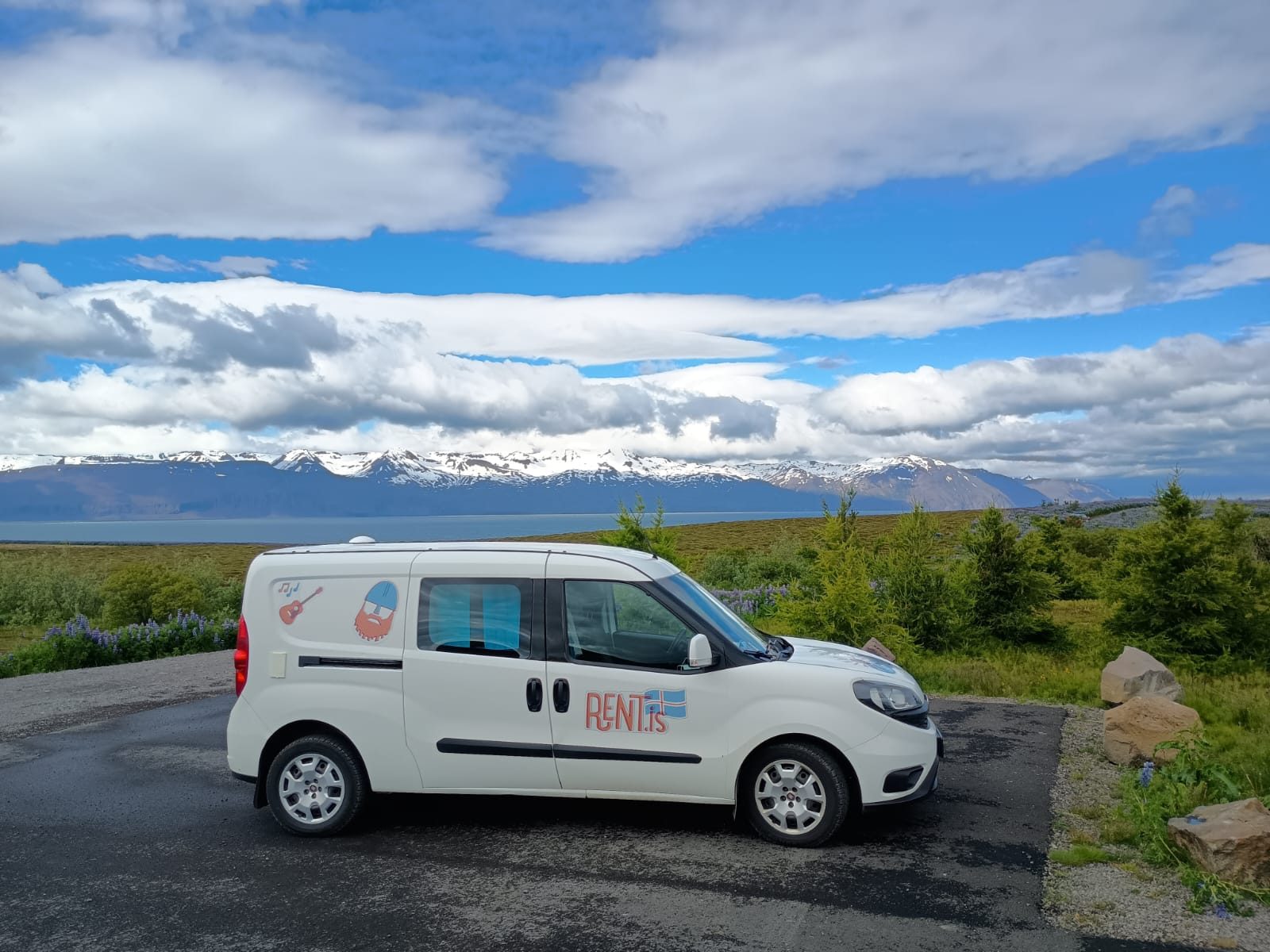 Rent.is Fiat Doblo camper parked at a viewpoint with snowy mountains behind