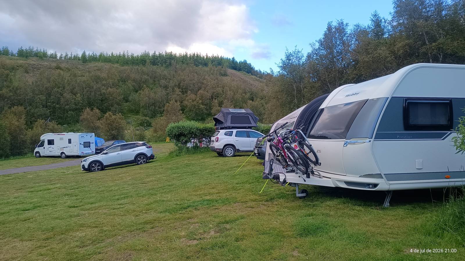 Campers and caravans parked on the grass at a forest campsite in North Iceland