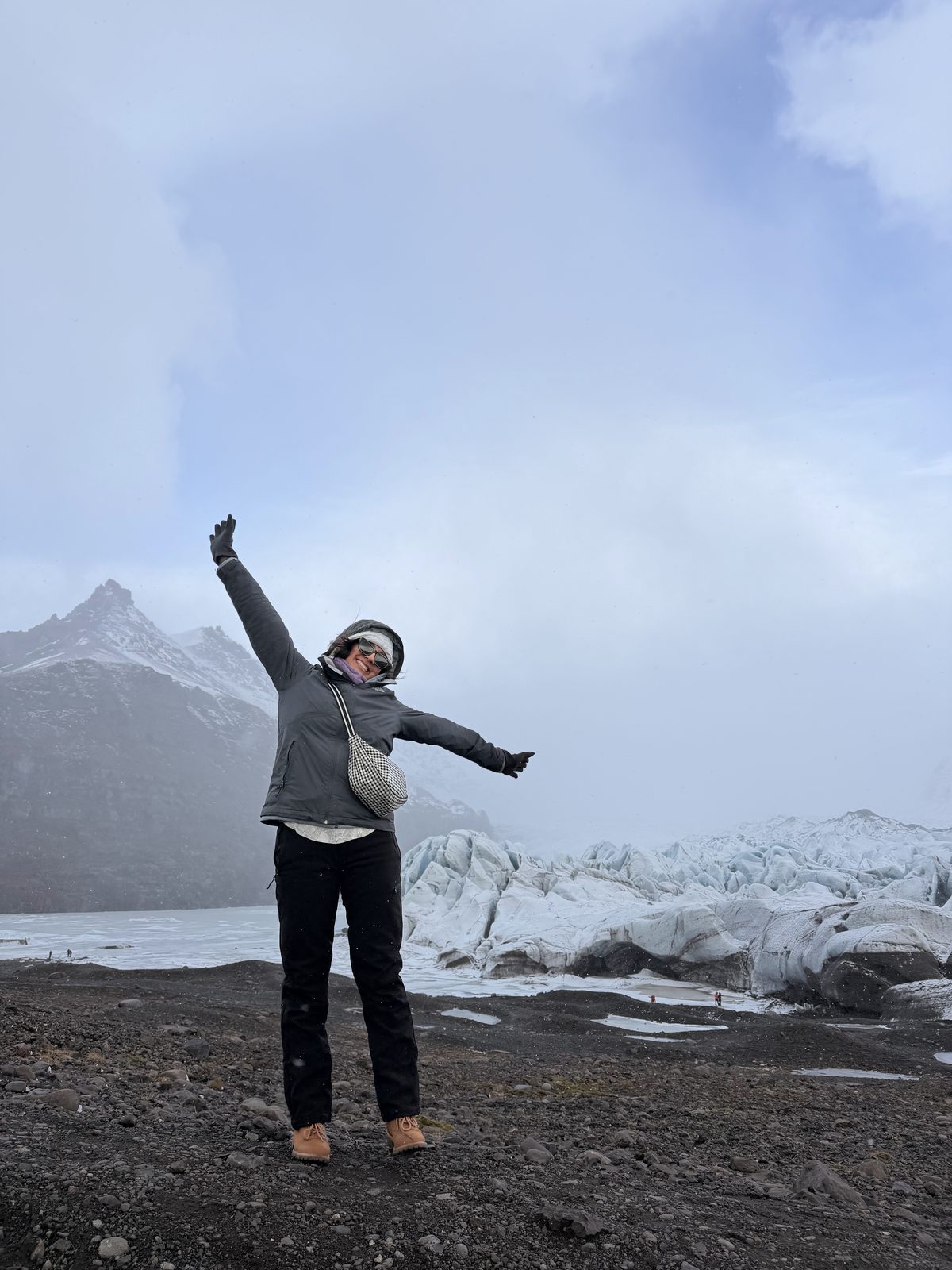 Arms outstretched beside an icy glacier lagoon in South Iceland