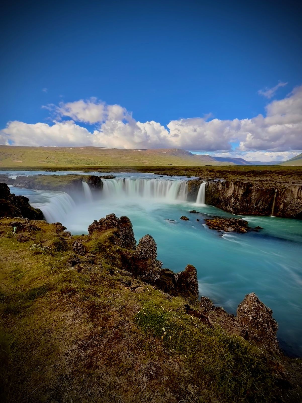 Turquoise water pouring over the horseshoe-shaped Goðafoss waterfall in North Iceland