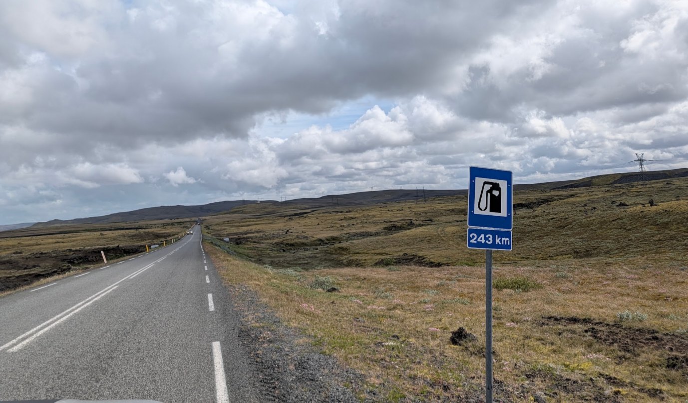 Blue road sign showing no petrol station for the next 243 km on an empty road in Iceland