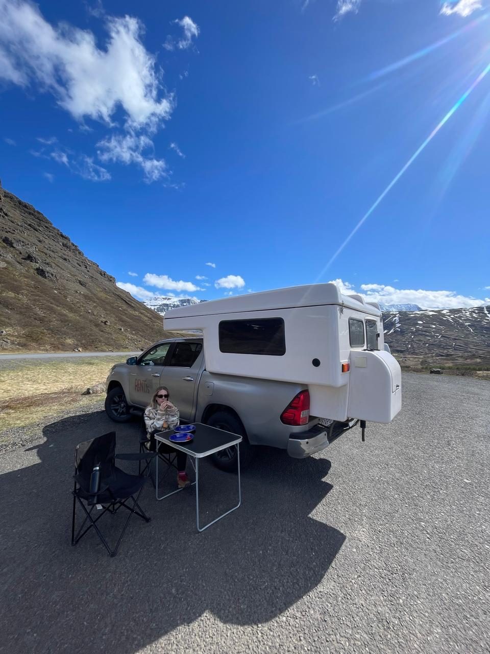 Roadside picnic with camping chairs and table beside the Hilux camper and snowy mountains