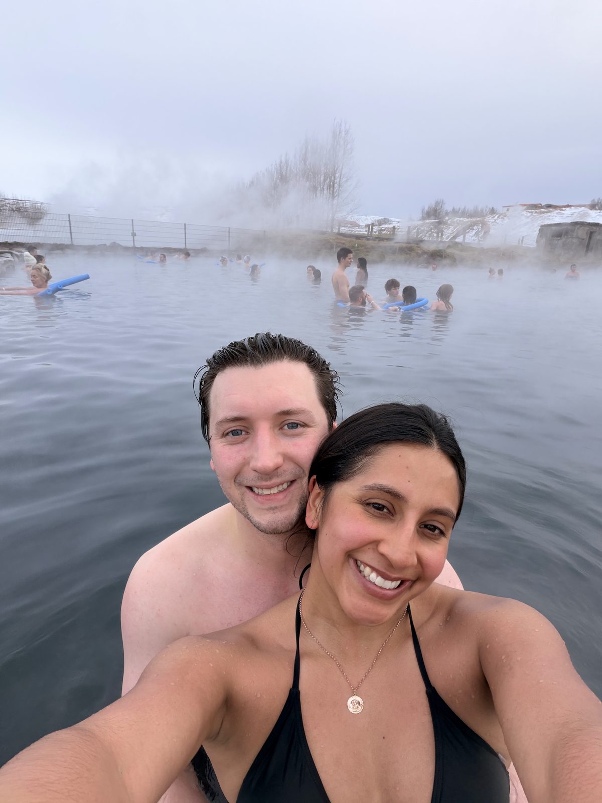 Couple taking a selfie in the steaming Secret Lagoon hot spring in Flúðir