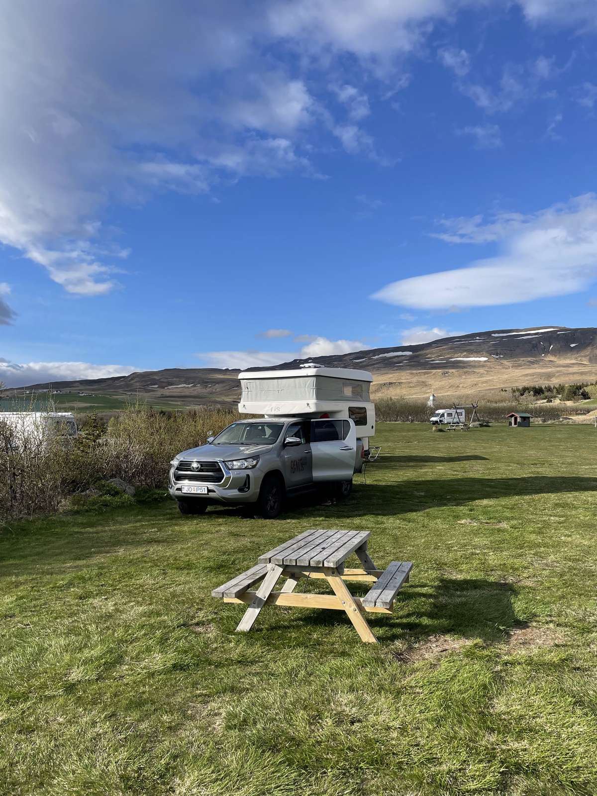 Toyota Hilux 4x4 camper with its pop-up roof, parked on a campsite in sunshine in Iceland