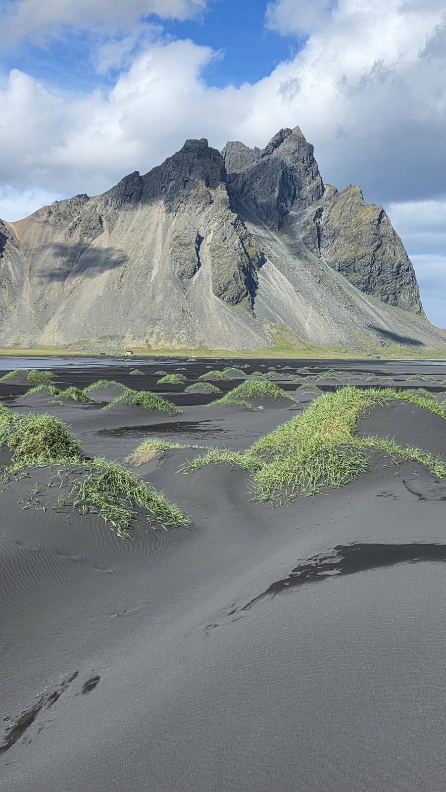 Jagged Vestrahorn mountain rising above grassy black sand dunes at Stokksnes