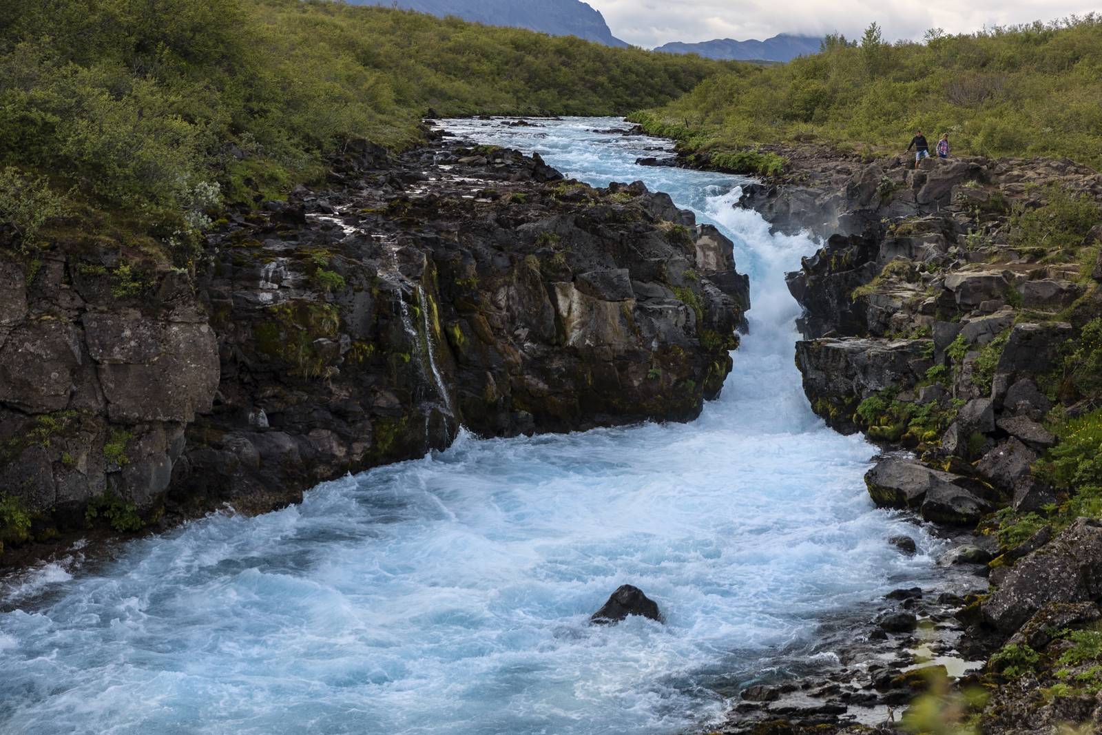 Turquoise waterfall rushing through a rocky gorge on the Brúará river trail